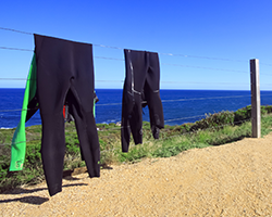 wetsuits drying on fence